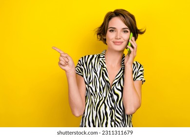 Portrait of positive cheerful woman wear striped blouse talk on phone directing at sale empty space isolated on yellow color background - Shutterstock ID 2311311679