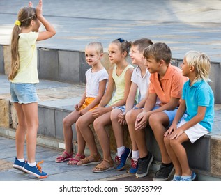 portrait of positive children spending time outside and playing charades 