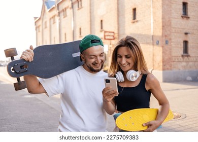 Portrait of positive couple walking with skateboards and smartphones outdoors.
 - Powered by Shutterstock