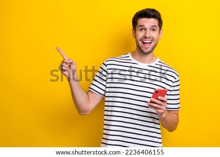 Portrait of positive crazy person toothy smile hold telephone direct finger empty space isolated on yellow color background