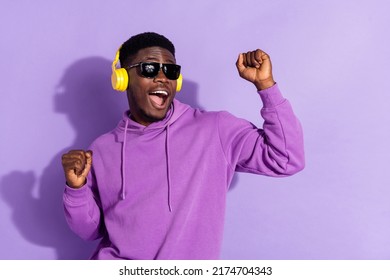 Portrait of positive excited carefree person raise fists listen single song isolated on violet color background - Powered by Shutterstock