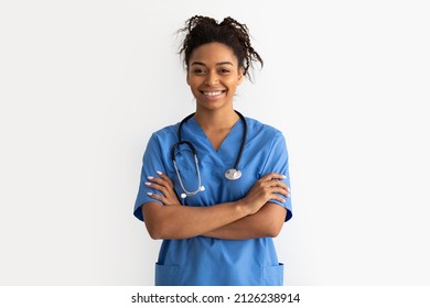 Portrait of positive female African American doctor or nurse posing with crossed arms and smiling looking at camera isolated over white studio background wall, lady wearing blue coat and stethoscope - Powered by Shutterstock