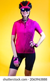 Portrait Of Positive Female Road Cyclist In Professional Sport Outfit Posing Against Yellow Background.Vertical Shot