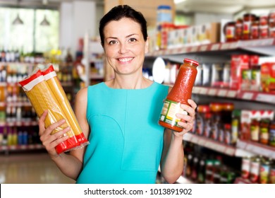 Portrait of positive female in the shop holding spaghetti indoors