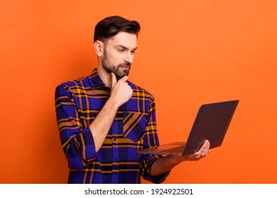 Portrait Of Positive Focused Person Arm On Chin Look Interested Laptop Display Isolated On Orange Color Background