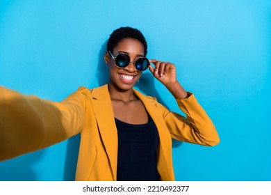 Portrait of positive friendly blogger make selfie arm touch glasses isolated on blue color background - Powered by Shutterstock