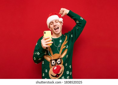 Portrait of a positive guy in casual clothes listening to music in headphones with a smartphone in his hand and dancing with his eyes closed. Cheerful young man having fun in headphones - Powered by Shutterstock