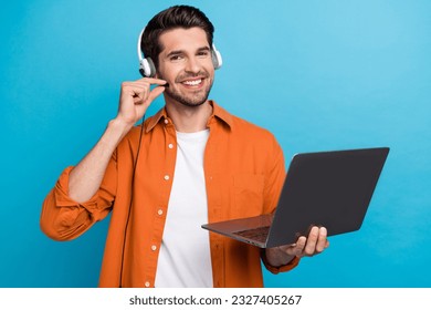 Portrait of positive handsome guy helpdesk operator hand touch headset microphone use netbook isolated on blue color background