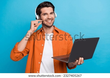 Portrait of positive handsome guy helpdesk operator hand touch headset microphone use netbook isolated on blue color background