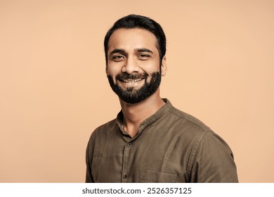 Portrait of positive, handsome indian man smiling and posing isolated on beige background. Confident fashion model in studio. Advertisement concept - Powered by Shutterstock