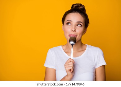 Portrait of positive inspired girl hipster lick lips spoon look copyspace feel interested about what she will eat breakfast wear white t-shirt isolated over bright shine yellow color background