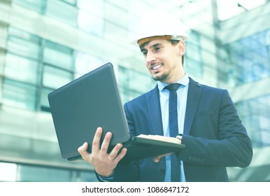 Portrait of positive male architect working at the laptop outdoors - Shutterstock ID 1086847172