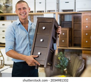 Portrait Of Positive Man Choosing Dressing Table In Furniture Store