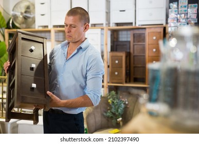 Portrait Of Positive Man Choosing Dressing Table In Furniture Store