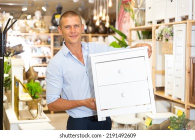 Portrait Of Positive Man Choosing Dressing Table In Furniture Store