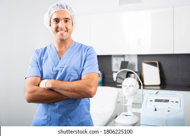 Portrait Of Positive Man Doctor Of Clinic Of Aesthetic Medicine Wearing Blue Overall Meeting Client