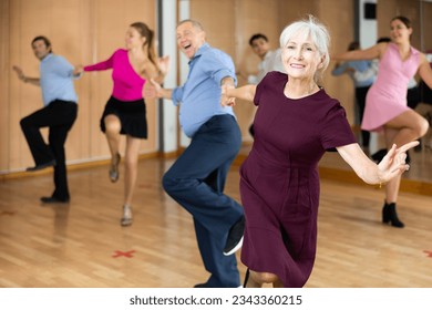 Portrait of positive older woman enjoying active dancing during group training in dance studio.. - Powered by Shutterstock