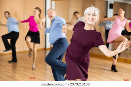 Portrait of positive older woman enjoying active dancing during group training in dance studio.. - Powered by Shutterstock