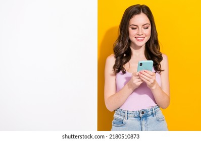 Portrait of positive pretty girl hold use telephone chatting typing post comment isolated on yellow color background