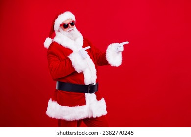 Portrait of positive santa claus indicate fingers empty space ad christmas event isolated on bright red color background