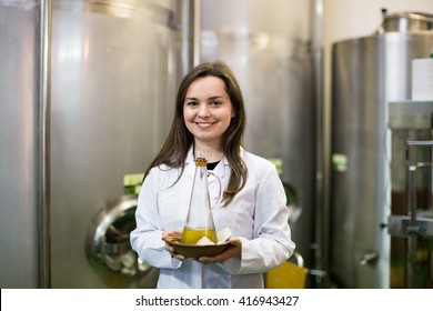 Portrait of positive smiling female posing with olive oil containers inside factory - Powered by Shutterstock