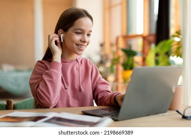 Portrait Of Positive Teen Girl In Earpods Using Laptop, Studying Online At Home, Happy Schoolgirl Looking At Pc Screen, Watching Webinar, Online Course, Doing Homework