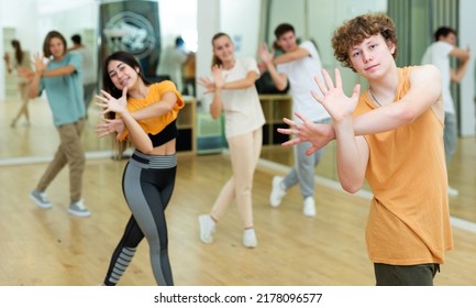 Portrait Of Positive Teenager Learning Dynamic Dance Moves With Group Of Teens In Choreography Class