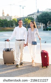 Portrait of positive traveling young spouses strolling with luggage along city street on spring day - Shutterstock ID 2186111227
