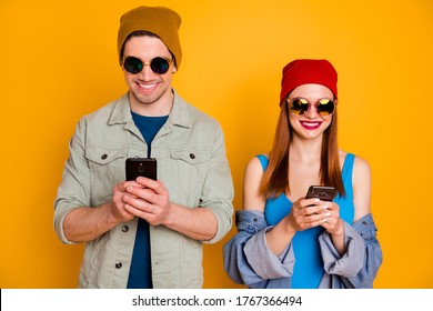 Portrait of positive two people students bloggers man woman use smartphone texting typing social media wear sunglass shirt denim jeans jacket isolated bright shine color background