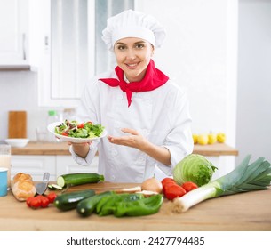 Portrait of positive woman chef presenting salad - Powered by Shutterstock