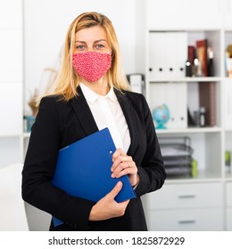 Portrait Of Positive Woman Manager In Medical Mask Holding Clipboard In Office While Working Day