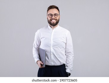 Portrait Of Positive Young Guy In Formal Wear Holding Tablet Computer Over Light Grey Studio Background. Cheerful Millennial Man With Touch Pad Posing And Smiling, Looking At Camera