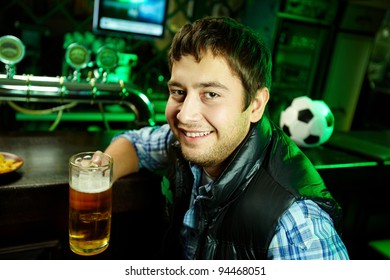 Portrait Of A Positive Young Man Holding A Mug Of Beer And Looking At Camera