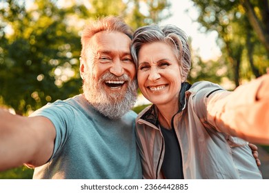 Portrait of positive,confident,happy,smiling senior couple holding camera phone taking photo.Modern attractive gray haired man with beard and beautiful elegant senior lady.                             - Powered by Shutterstock