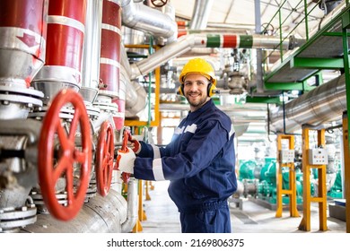 Portrait Of Power Plant Worker Engineer Standing By Natural Gas Pipelines And Closing The Valve.