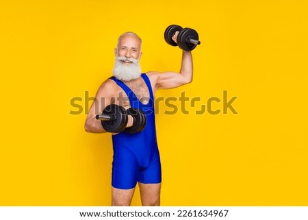 Portrait of powerful cheerful granddad toothy smile arms lifting dumbbells isolated on yellow color background