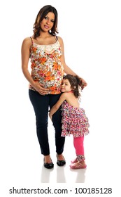 Portrait Of Pregnant Hispanic Mother With Daughter Standing Over White Background