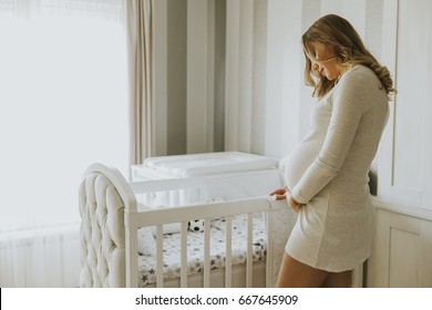 Portrait Of Pregnant Woman Setting Up Baby Crib In The Room