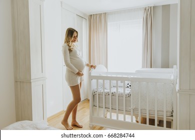 Portrait of pregnant woman setting up baby crib in the room - Powered by Shutterstock