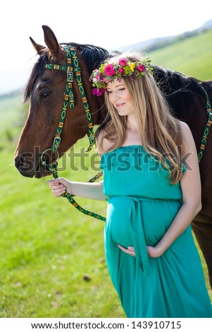 Portrait of pregnant woman in wreath near horse