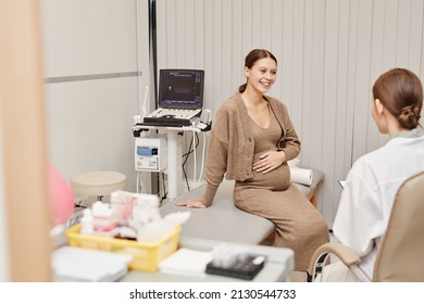 Portrait Of Pregnant Young Woman Smiling Happily While Listening To Doctor In Ultrasound Exam Room