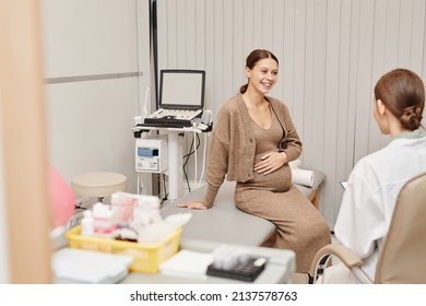 Portrait Of Pregnant Young Woman Smiling Happily While Listening To Doctor In Ultrasound Exam Room