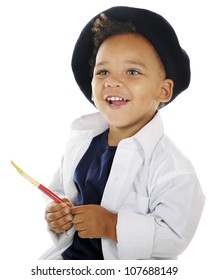 Portrait Of A Preschool Artist Delightedly Holding A Paint Brush In His Smock And French Beret.