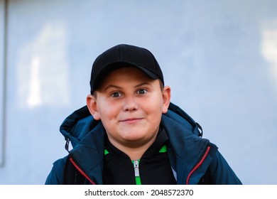 Portrait Of Preteen Surprised Happy Boy Close-up In Jacket And Cap Standing Outdoor. Funny Teen Child With Bulge Eyes. Handsome School Kid Outside.