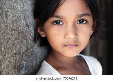 Portrait of a pretty 8 year old Filipina girl in poverty-stricken neighborhood, natural light.
