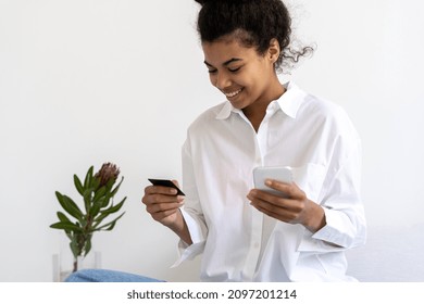 Portrait Of Pretty African American With Credit Card And Smartphone In Hands. Making Online Payments. Millenial Lady Paying For Shopping From Home