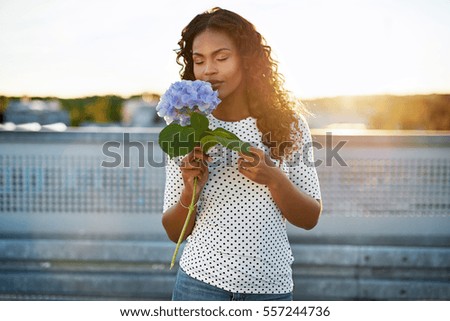 Portrait of a pretty african american woman smelling a flower
