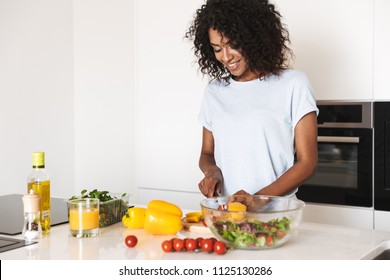 Portrait of a pretty afro american woman making a healthy salad at the kitchen
