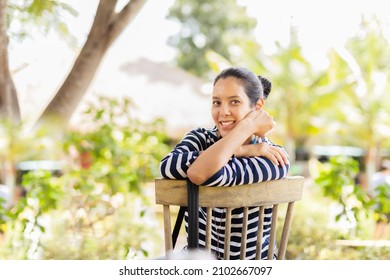 Portrait Of Pretty Asian Middle Age Woman Sitting On A Chair In The Garden