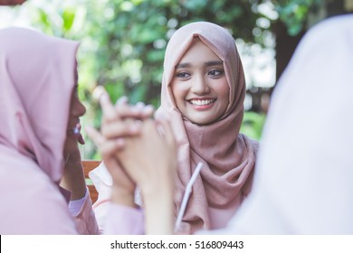 portrait of pretty asian muslim woman having fun in cafe together with friends
